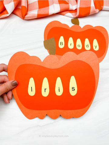 Pumpkin-shaped craft with seed letters spelling 'Iris' and 'Brody' on a white background.