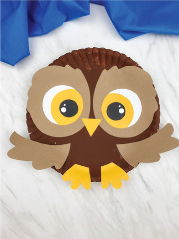 paper plate owl craft on marble background with blue fabric 