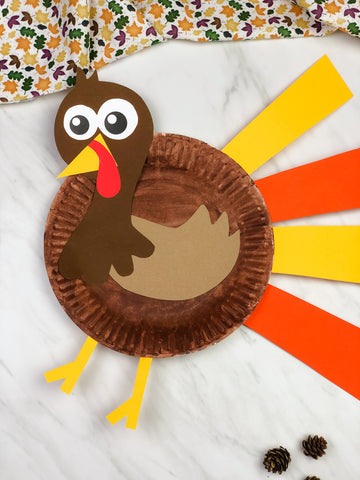 Paper plate turkey craft with colorful feathers on a white background