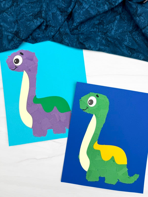 Two torn paper dinosaur crafts on white background with dark blue fabric on top