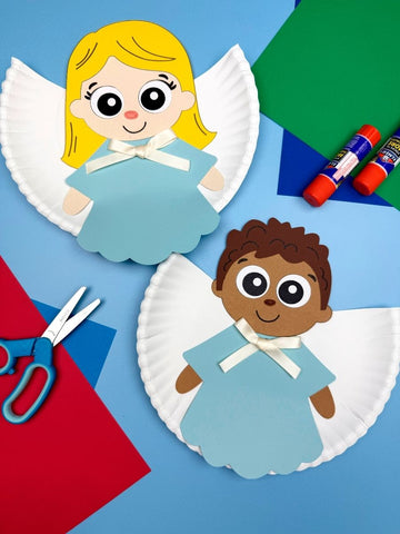 Two paper plate angels with colorful craft supplies on a blue background