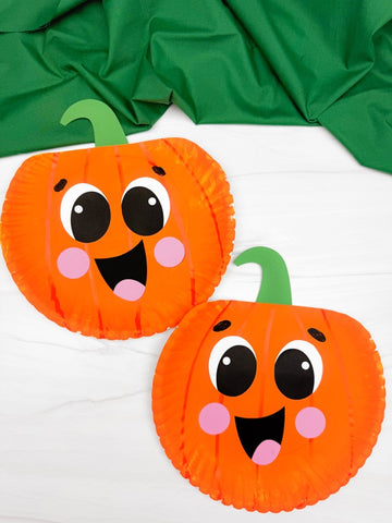 Two paper plate pumpkins with faces on a white background