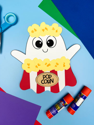 Handmade craft of a popcorn ghost craft with glue sticks and scissors on a colorful background