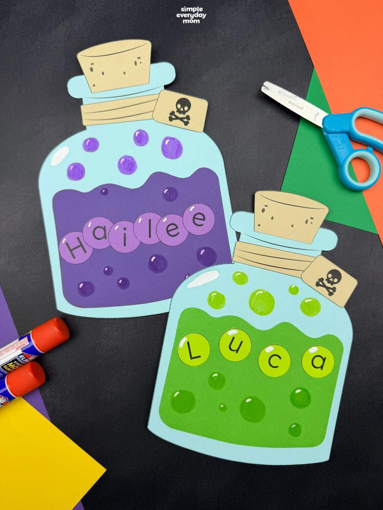 Two personalized potion craft cutouts shaped like potion bottles, one with purple slime and the other with green slime, displayed on a black background with craft supplies including scissors, markers, and colored paper.