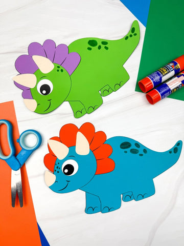 Colorful dinosaur crafts with markers, glue sticks, and scissors on a white background
