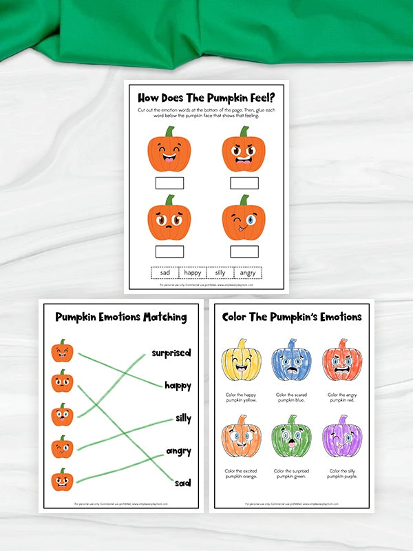 Three printable pumpkin-themed worksheets are arranged on a white fabric background with a green cloth at the top. The worksheets include pumpkin face illustrations, emotion matching, and coloring activities.