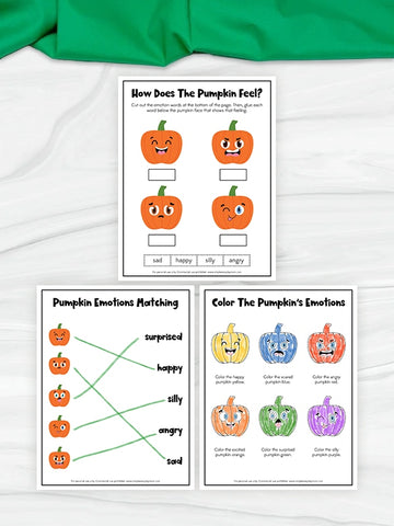 Three printable pumpkin-themed worksheets are arranged on a white fabric background with a green cloth at the top. The worksheets include pumpkin face illustrations, emotion matching, and coloring activities.