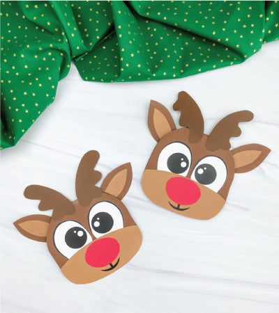 Two reindeer Christmas cards on a white background with a green fabric on the top.