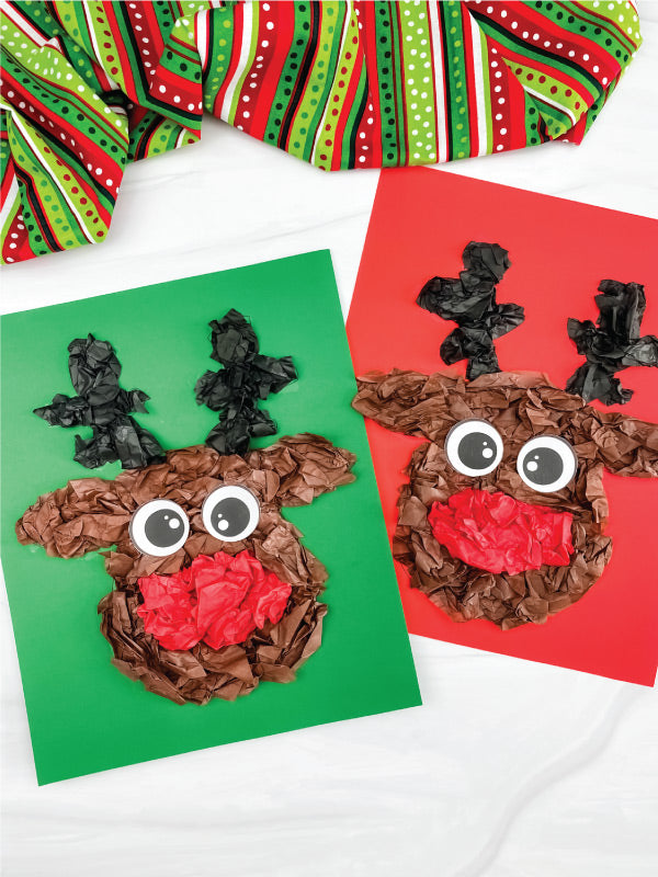 Two reindeer crafts made from tissue paper and glue on a white background with green and red fabric.