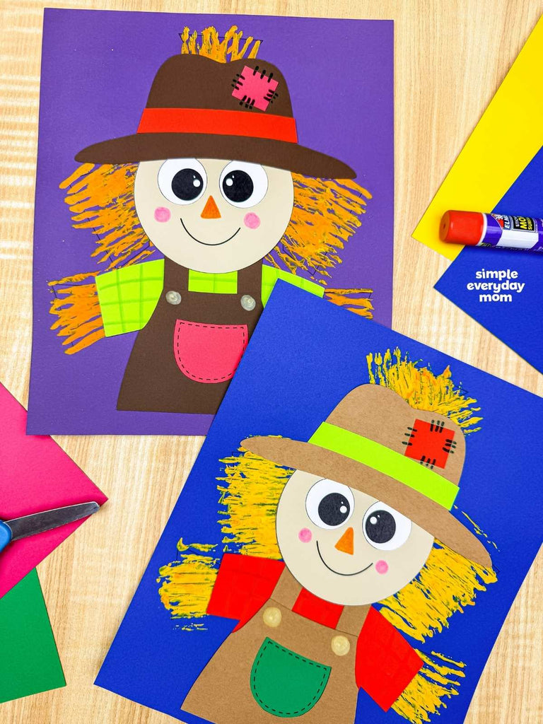 Two fork painted scarecrow crafts on wood background with colorful paper, scissors and glue stick. 