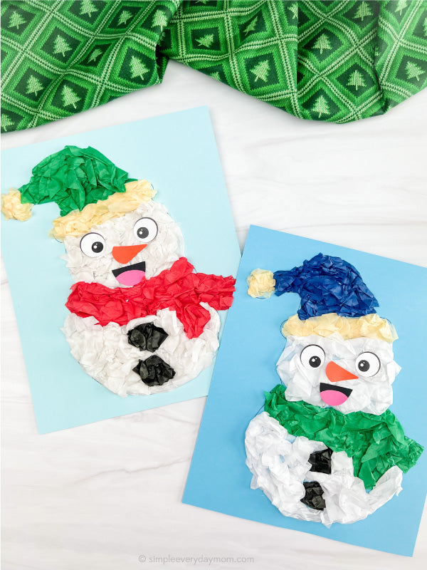 Two snowman-themed tissue paper crafts on blue papers with a green and white patterned fabric in the background.