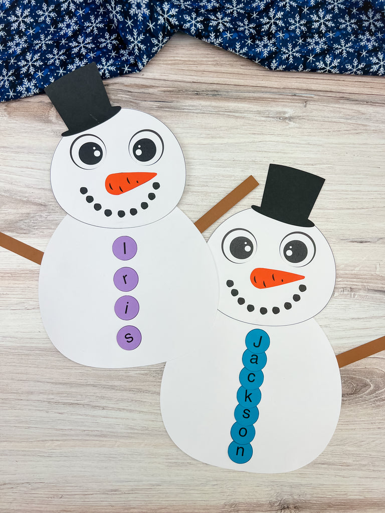 Two paper snowmen with names 'Iris' and 'Jackson' on a wooden surface.