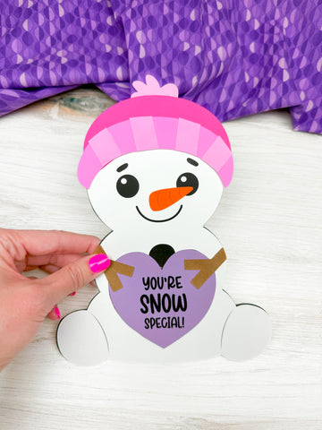 hand holding snowman Valentine craft on washed wood background