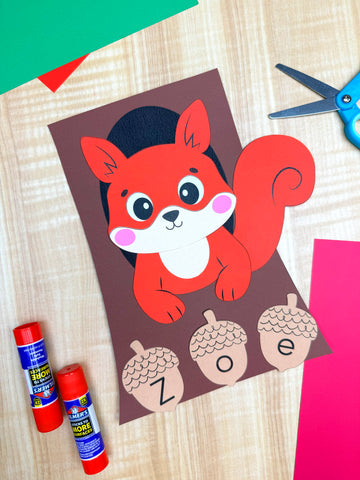 squirrel name craft project on wood background with colorful paper, scissors, and glue sticks 