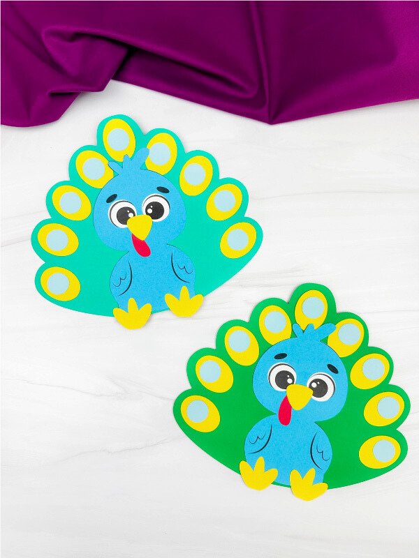 Two colorful turkeys disguised as peacocks on a white background with a purple fabric at the top.