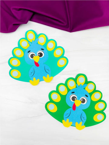 Two colorful turkeys disguised as peacocks on a white background with a purple fabric at the top.