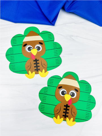 Two paper craft turkeys disguised as a football with a marble and blue fabric background.