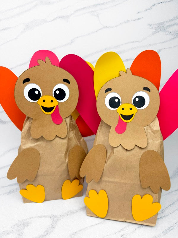 Two paper bag turkeys with colorful feathers on a white background