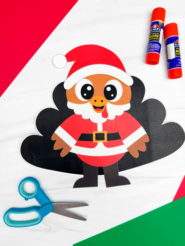 Paper cutout of a turkey in Santa Claus outfit with glue sticks and scissors on a red, white, and green striped background.