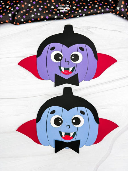 Two vampire pumpkin crafts on white surface with black fabric on top. 