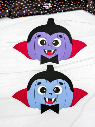 Two vampire pumpkin crafts on white surface with black fabric on top. 