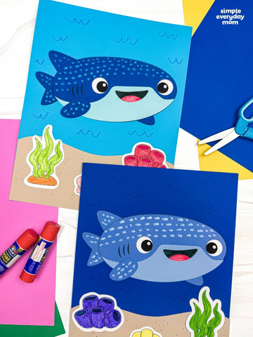 Two whale shark paper crafts on colorful background with scissors and glue